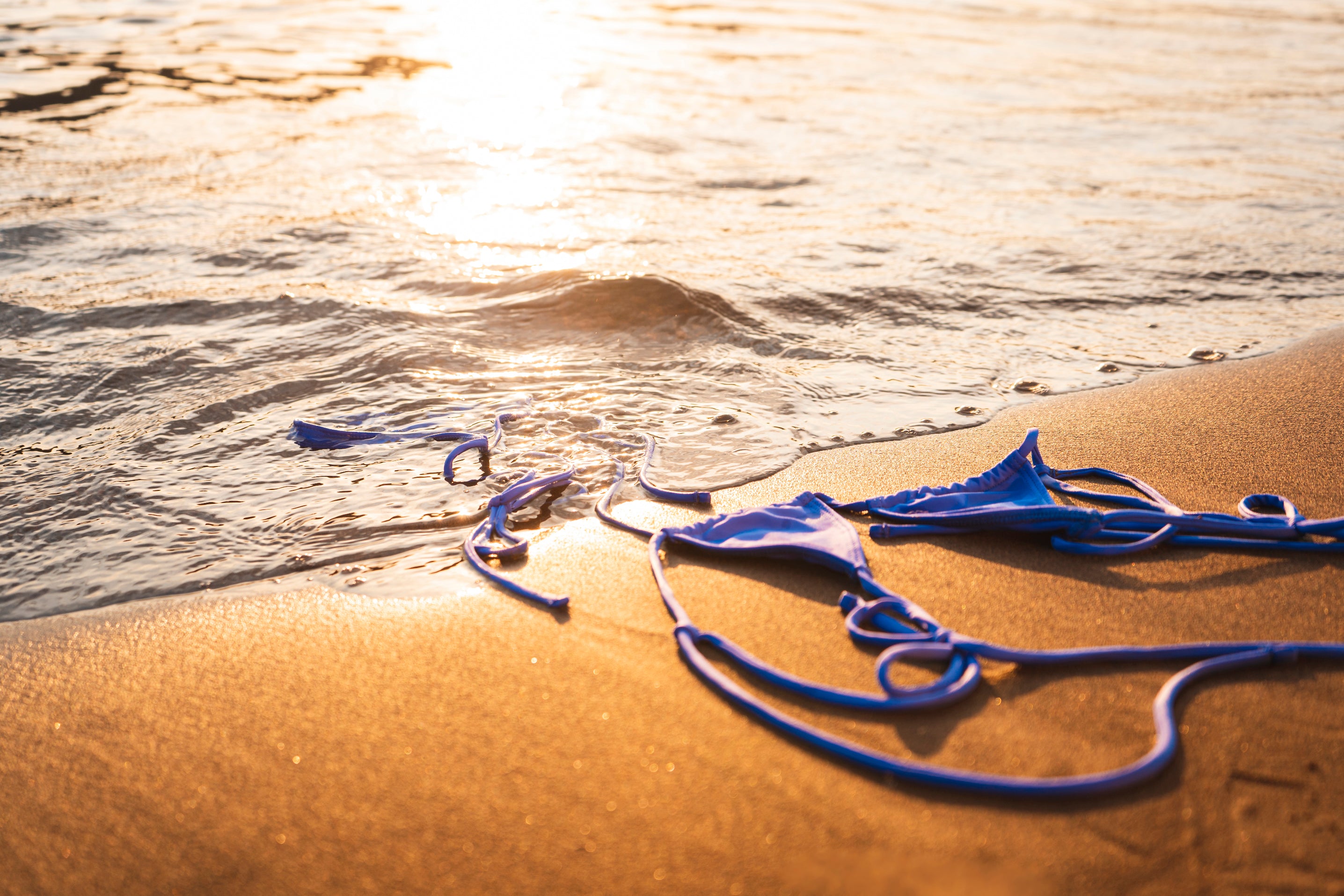 Bikini azul Bum: Sumergido bajo una ola en la orilla de una playa de arena dorada. Descubre la libertad y calidad de Bum Swim. Moda para mujeres que destaca, disponible ahora.