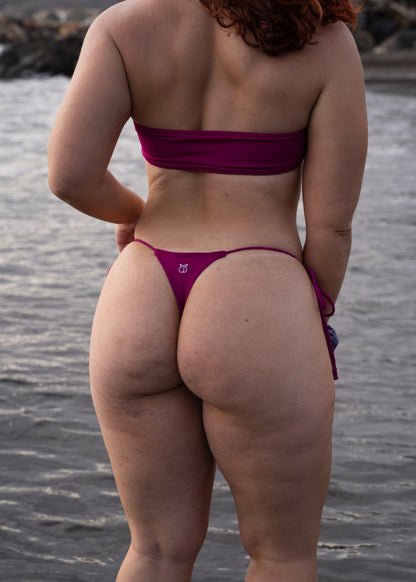 Chica con bikini tanga de moda 2024, posando en la playa con un bikini que potencia el culo